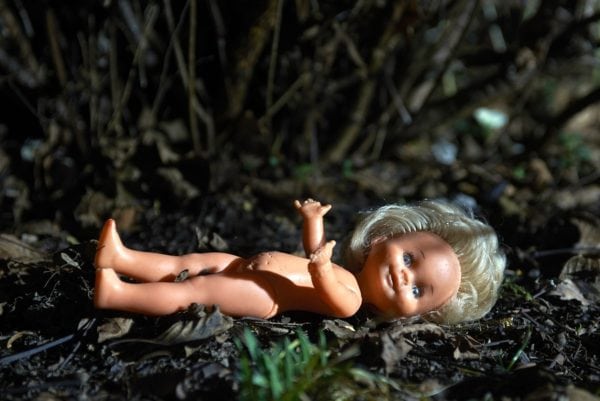 Child safety doll lying on the ground in a natural outdoor setting.