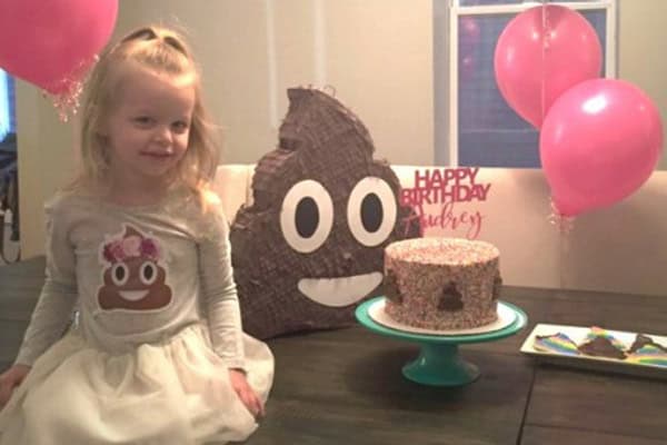 Cute girl celebrating with poo emoji-themed birthday cake and decorations.