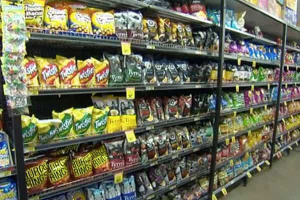 Shelves of snack foods with cartoon characters on packaging in a supermarket aisle.
