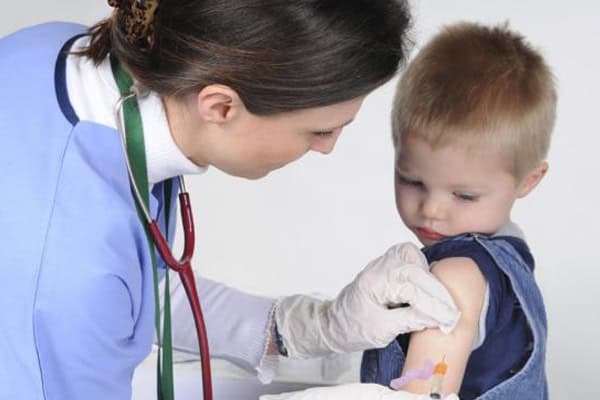 Nurse administering COVID-19 vaccine to young boy in clinic.