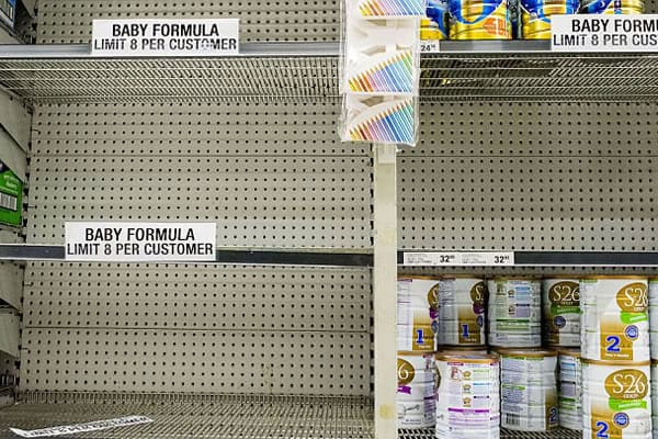 Empty shelves with signs indicating limits on baby formula purchases.