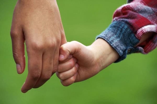 Child and adult hand holding for foster care support.