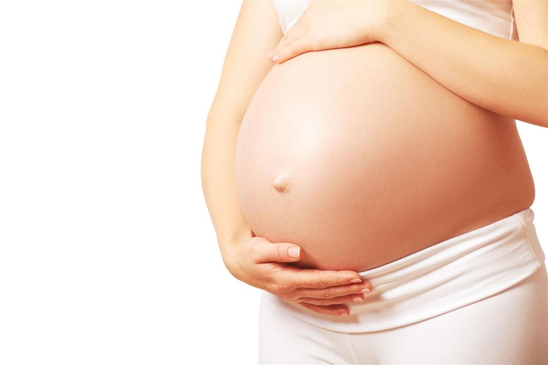 Pregnant woman gently cradling her belly during pregnancy.