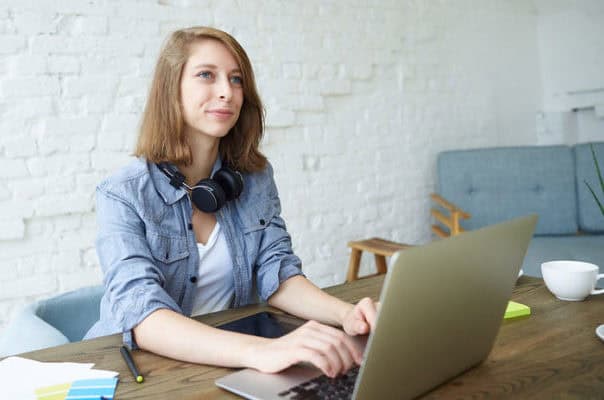 Young woman working on a laptop at home, creating a blog to monetise her content.