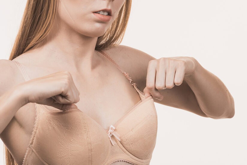 Woman adjusting her nude bra, highlighting confidence after breast surgery.