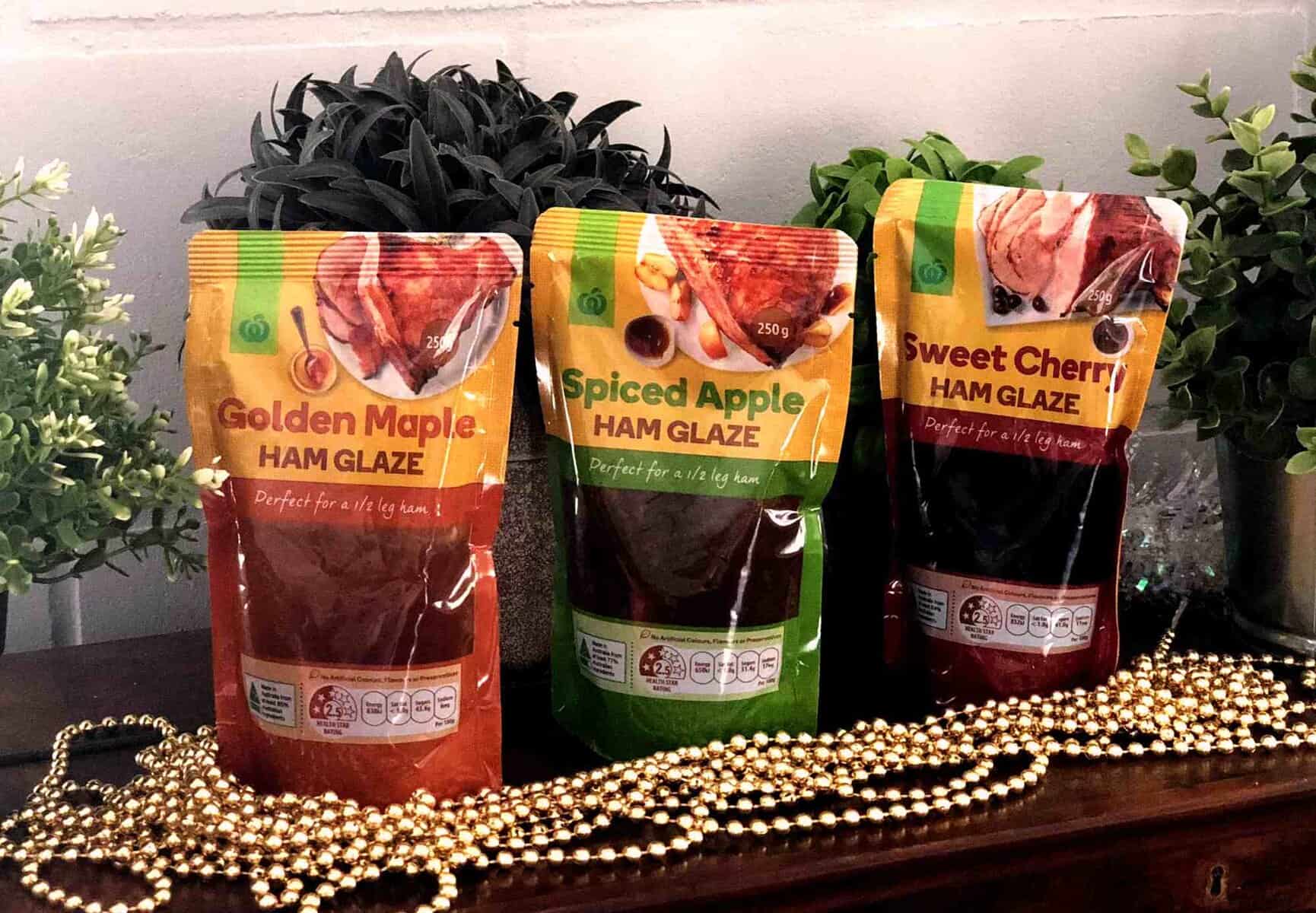 Assorted Woolworths ham glazes including Golden Maple, Spiced Apple, and Sweet Cherry on a wooden su.