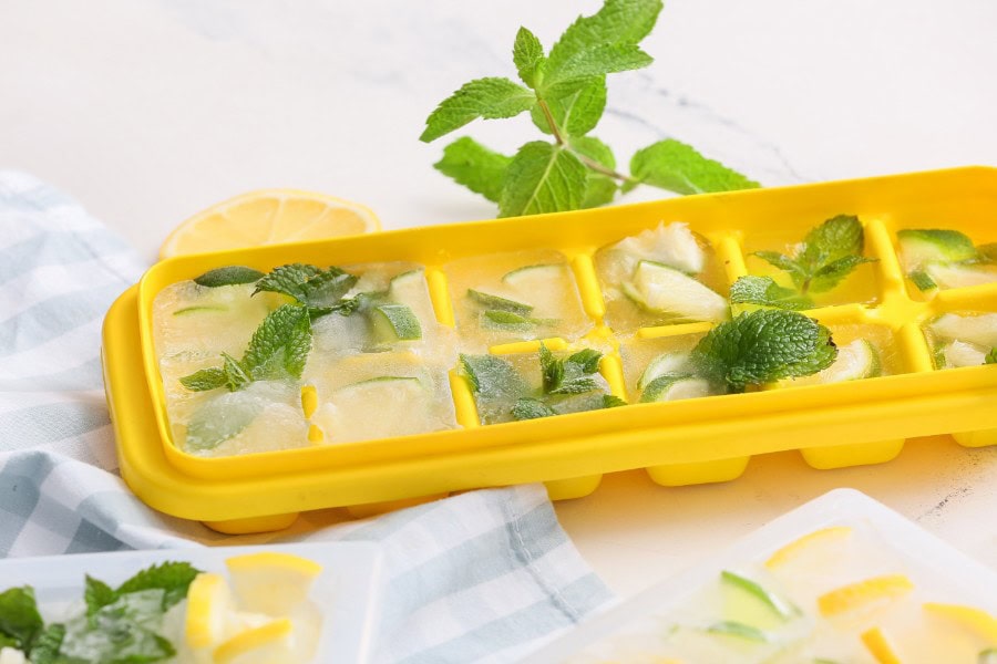 Ice cube tray with lemon and mint ice cubes for refreshing drinks.