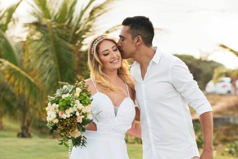 Wedding couple in a tropical garden with palm trees and lush greenery.
