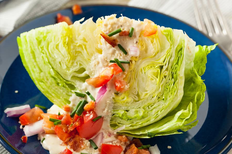 Crisp lettuce wedge topped with creamy blue cheese dressing and fresh vegetables.
