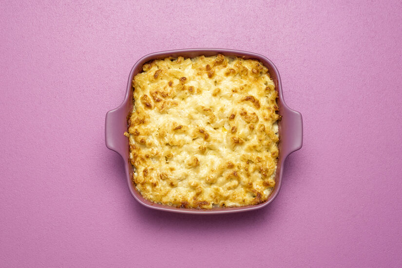 Microwave cheese sauce in a purple dish on pink background.