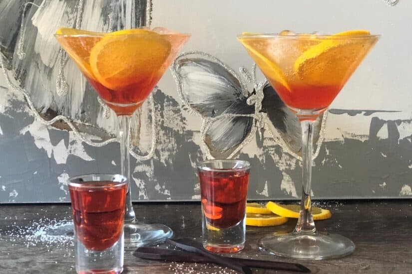 Aperol and orange spritzers served in cocktail glasses with slices of orange.