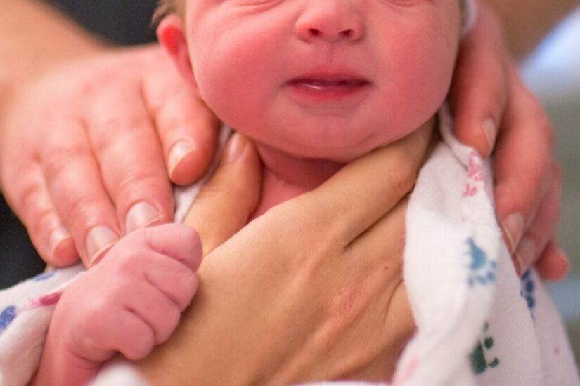 Newborn baby being held gently by a parent, capturing the emotional moment after birth.