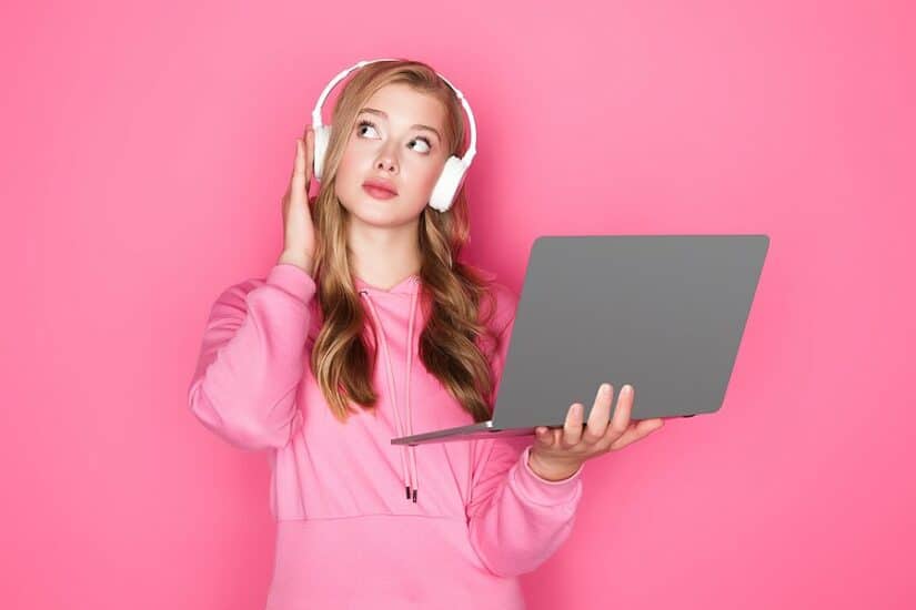 Young woman with headphones holding a laptop, working from home.
