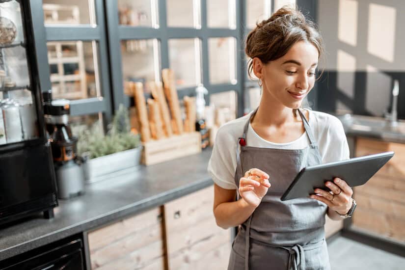 Woman using a tablet in a modern kitchen preparing to start a small batch food business
