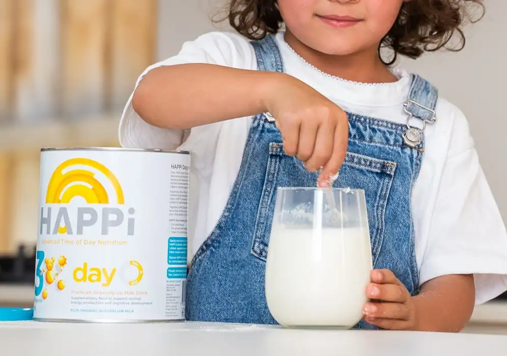 Baby formula in a tin can with a child pouring milk into a glass.
