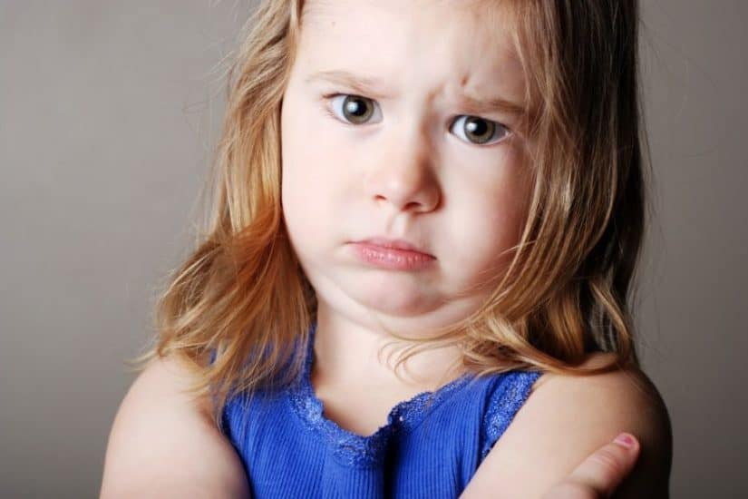 Child with a stubborn expression, showing frustration or defiance.