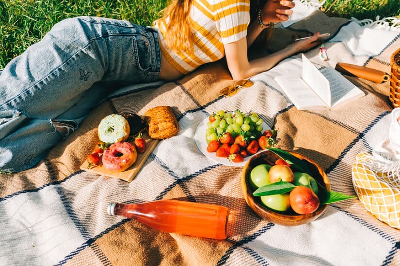 Comfortable picnic blanket with fresh fruit, drinks, and snacks for outdoor adventures.
