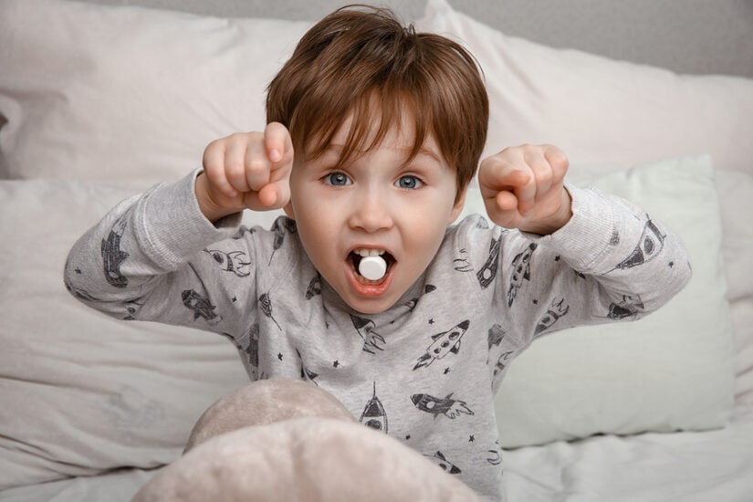 Young boy with a pill in his mouth, ready to swallow medication.