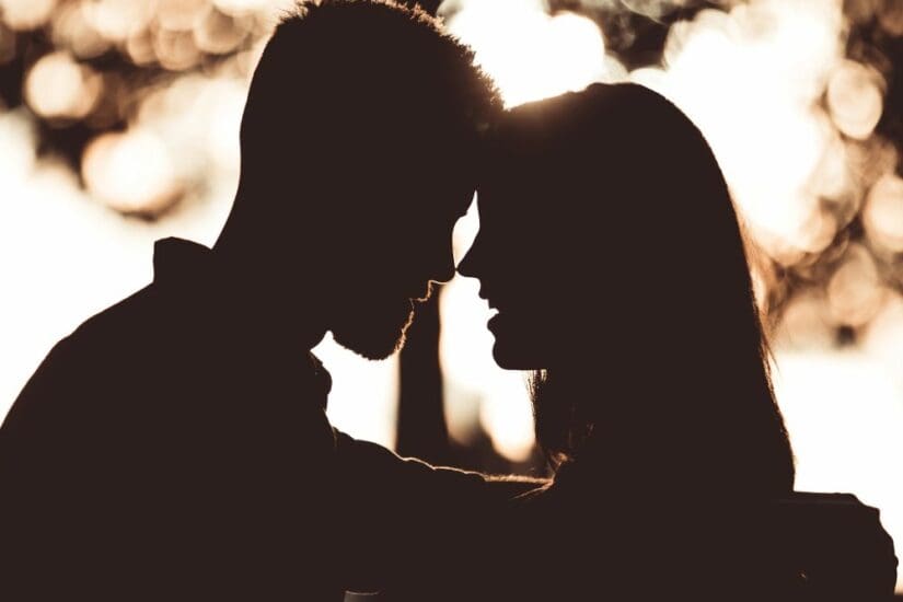 Silhouetted couple sharing an intimate moment at sunset, symbolising connection and romance.