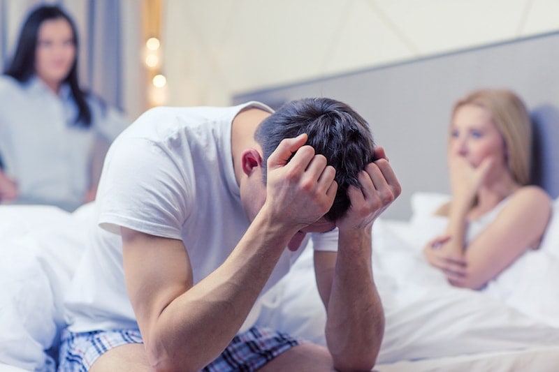 Man distressed over relationship problems with partner in bedroom.
