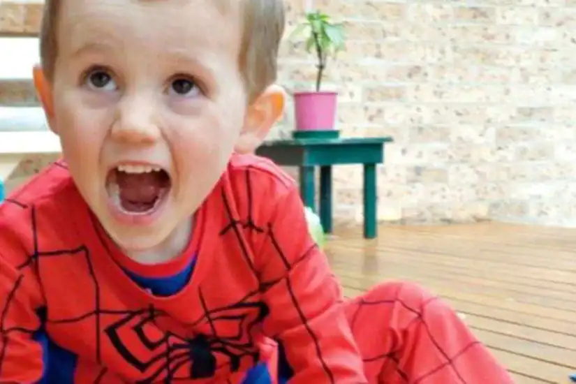 Child in Spider-Man costume with mouth open, outdoors, investigating case.