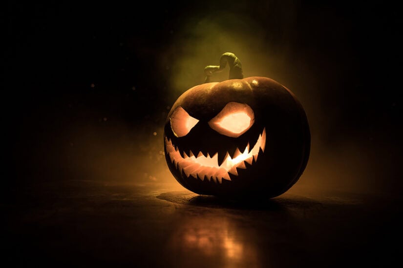 Spooky carved pumpkin with glowing eyes and jagged mouth for Halloween decorations.