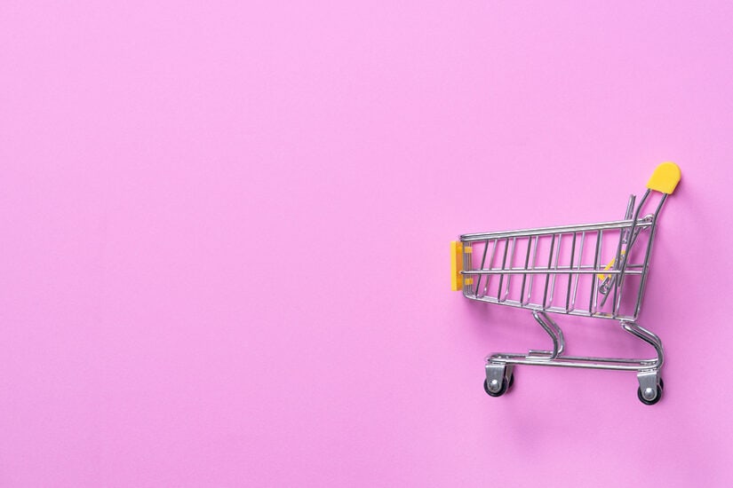 Miniature shopping cart on a pink background, symbolising consumer trends and shopping habits for mu.