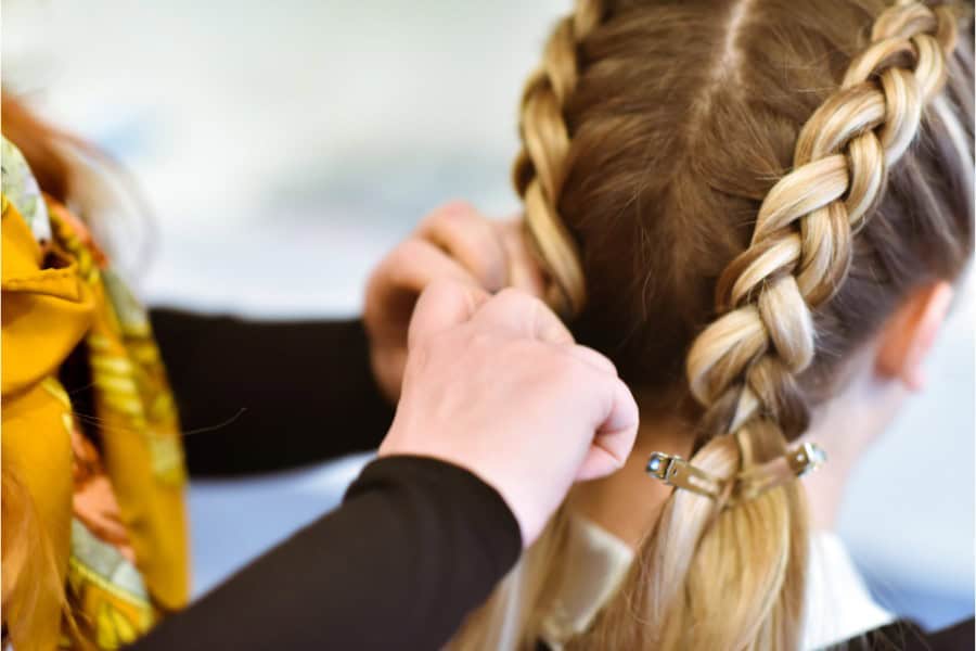 Close-up of a person creating double braids in a child's hair.