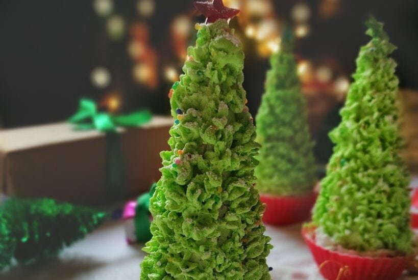 Festive cake cones decorated as Christmas trees with green icing and sprinkles.