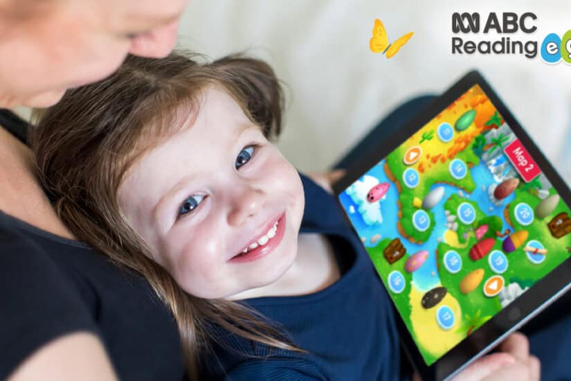 Happy child using ABC Reading Eggs educational app on tablet for learning fun.