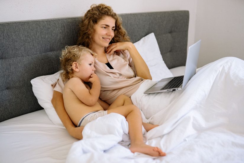 Mother and child watching a laptop together in bed, focusing on financial investment guidance for bu.