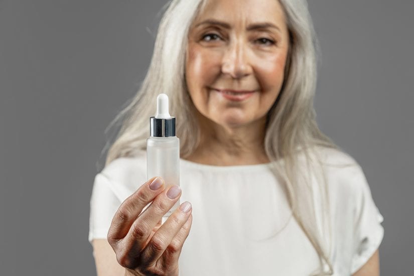 Woman holding skincare serum, promoting skincare brands for mature skin.