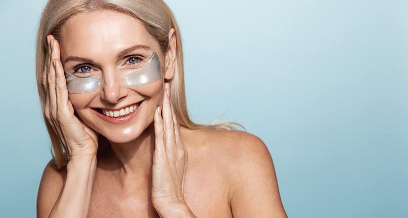 Woman applying eye masks for skincare, promoting healthy mature skin.