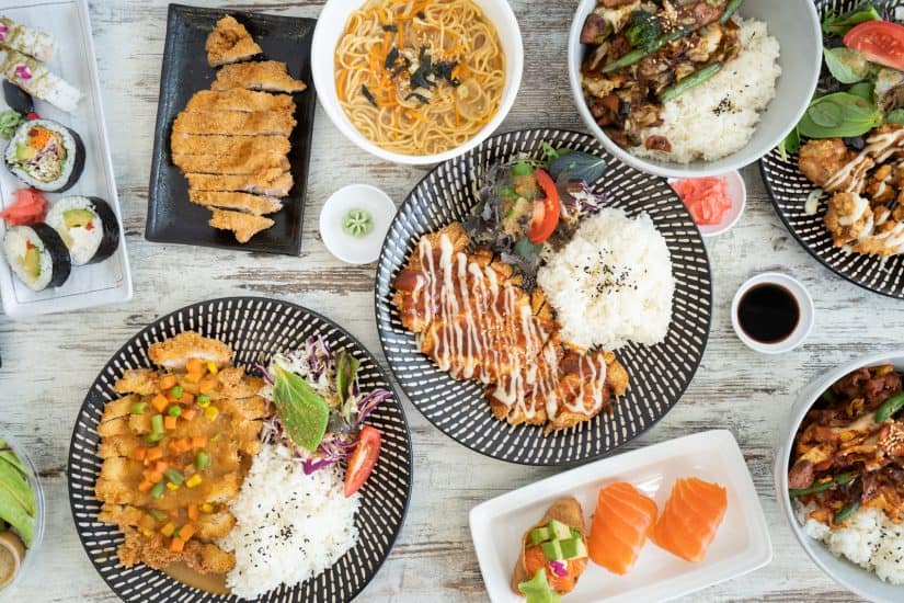 Asian family dinner with rice, sushi, and stir-fry dishes.