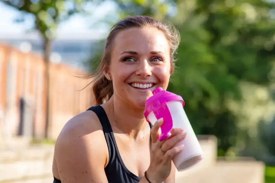 Woman enjoying a weight loss shake after workout in the backyard.