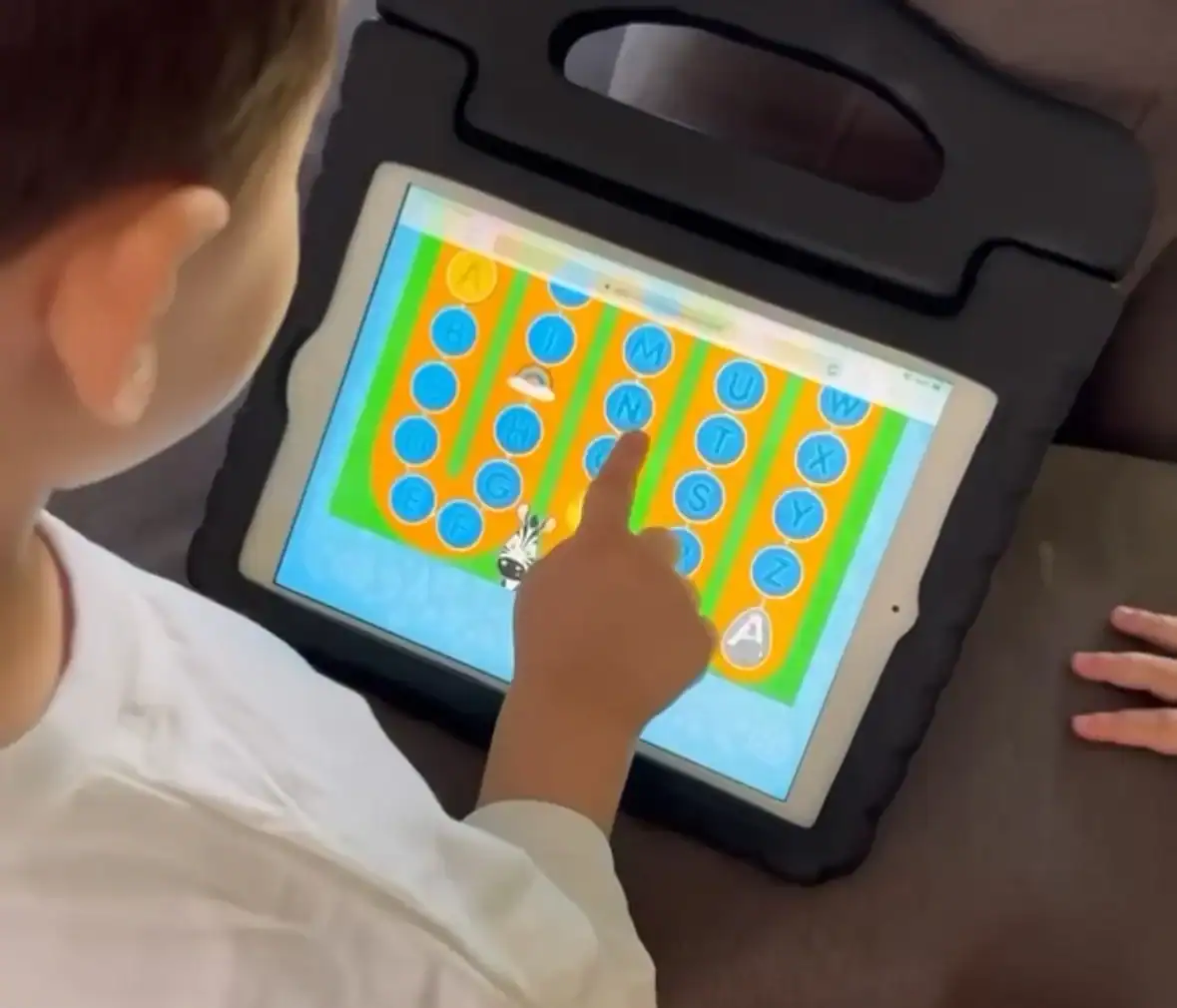 Child using tablet for educational game during Easter holidays.