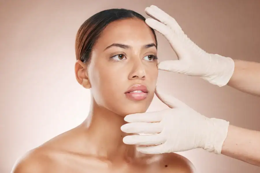 Woman undergoing a facial assessment as gloved hands cradle and frame her face