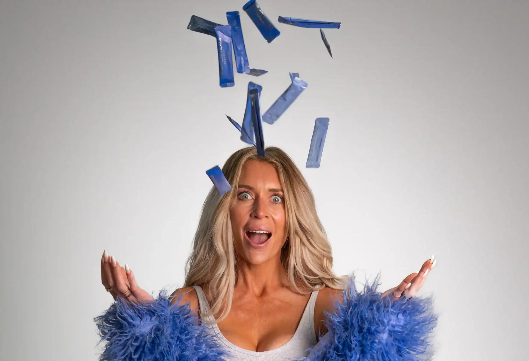 Woman with surprised expression and blue confetti falling around her.