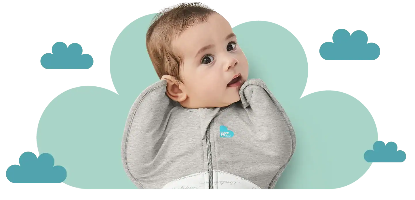 Adorable baby wearing a grey hoodie looking curious against a cloud themed background